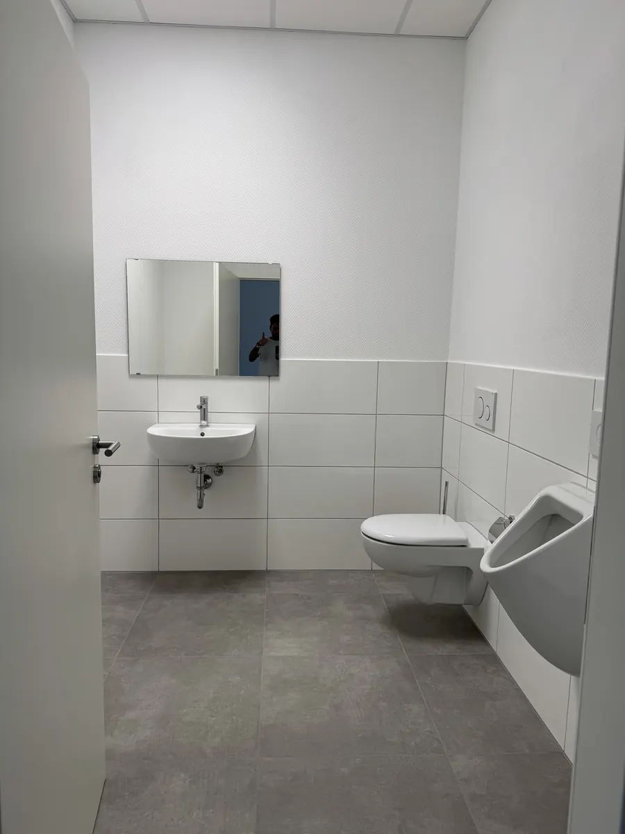 Im Erdgeschoss neu errichtete WC-Anlage mit weißen Fliesen